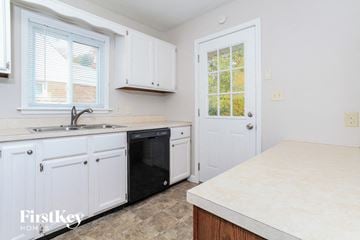 Cincinnati house for rent - a kitchen with white cabinets and a black dishwasher
