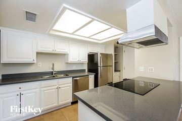 Tempe house for rent - A kitchen with white cabinets and a black counter top.