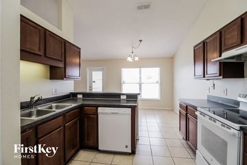 Poinciana house for rent - a kitchen with wooden cabinets and a white dishwasher and a sink