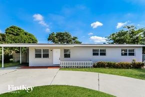 Boynton Beach house for rent - A white house with a red stripe and a white fence in front.
