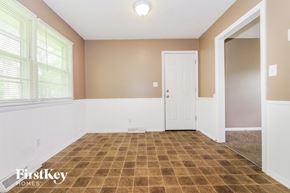 Blue Springs house for rent - A room with a brown tiled floor and a white door.