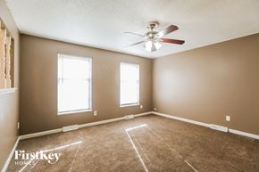 Kansas City house for rent - an empty living room with a ceiling fan and two windows