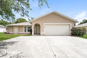 Cape Coral house for rent - a beige house with a driveway and a white garage door