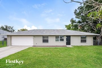 Cape Coral house for rent - a white house with a grassy yard and a black door