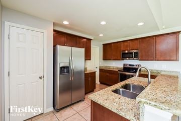 Cape Coral house for rent - a kitchen with granite counter tops and a stainless steel refrigerator