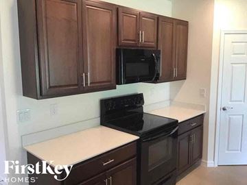 Cape Coral house for rent - a kitchen with dark wood cabinets and a black stove