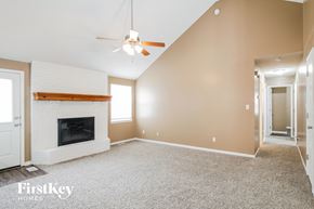 Raymore house for rent - A spacious room with a fireplace and a ceiling fan.
