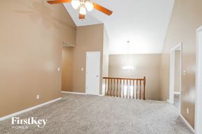 Raymore house for rent - A spacious room with a ceiling fan and a wooden railing.
