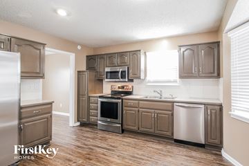 Raymore house for rent - A kitchen with wooden floors and brown cabinets.