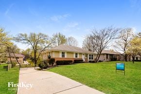 Lee's Summit house for rent - a home with a yard and a blue sign on the sidewalk