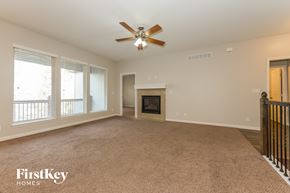 Raymore house for rent - an empty living room with a ceiling fan and a fireplace