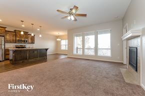 Raymore house for rent - an empty living room with a kitchen and a ceiling fan