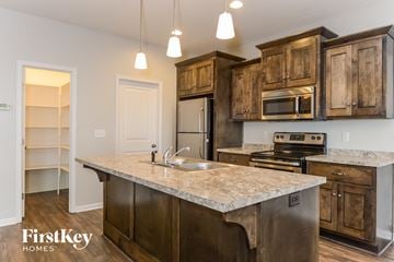 Raymore house for rent - a kitchen with wooden cabinets and a marble counter top