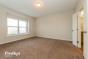 Raymore house for rent - a bedroom with a carpeted floor and a large window