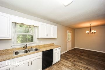 Newnan house for rent - A kitchen with white cabinets and a wooden floor.