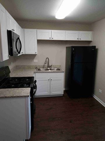 Glenwood house for rent - a kitchen with white cabinets and a black refrigerator