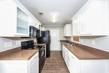 Summerville house for rent - a kitchen with white cabinets and black appliances and white counter tops