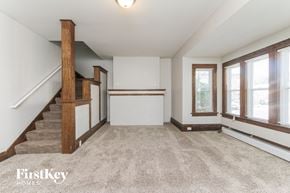 Aurora house for rent - an empty living room with a staircase and windows