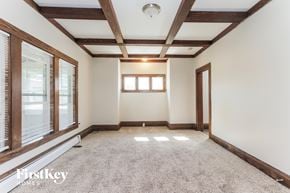 Aurora house for rent - an empty living room with white walls and wood beams