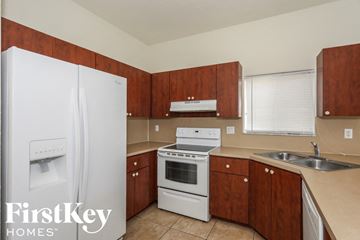 Homestead house for rent - A kitchen with a white fridge, stove and wooden cabinets.