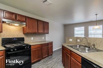 Houston house for rent - A kitchen with a black stove top oven and wooden cabinets.