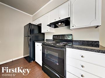 Duncanville house for rent - a kitchen with black appliances and white cabinets and a black refrigerator