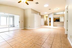 Tarpon Springs house for rent - an empty living room with a ceiling fan and tile flooring