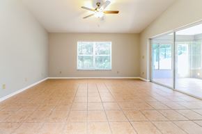 Tarpon Springs house for rent - an empty living room with a ceiling fan and a sliding glass door