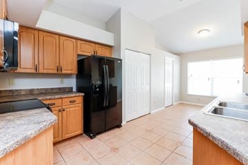 Tarpon Springs house for rent - a kitchen with wooden cabinets and a black refrigerator