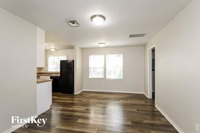 Florissant house for rent - A spacious room with wooden flooring and a black refrigerator.