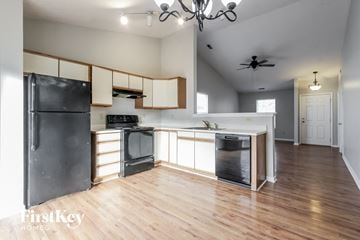 Indianapolis house for rent - a kitchen with white cabinets and black appliances and a wood floor