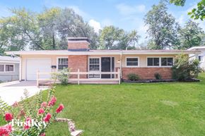 Florissant house for rent - A house with a red brick chimney and a white garage door.