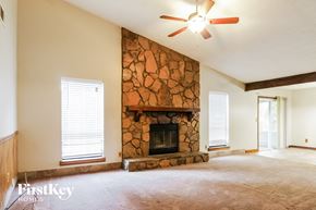 Acworth house for rent - A living room with a stone fireplace and a ceiling fan.