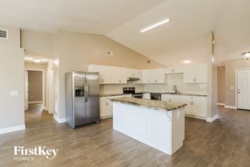 Poinciana house for rent - a large kitchen with stainless steel appliances and white cabinets
