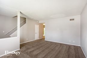 Indianapolis house for rent - A spacious room with a carpeted floor and a staircase on the left side.