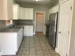 Helena house for rent - A kitchen with white cabinets and a tile floor.