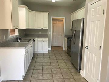Helena house for rent - A kitchen with white cabinets and a tile floor.