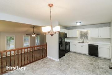 Dallas house for rent - a kitchen with white cabinets and a black refrigerator