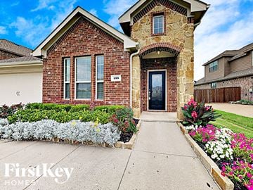 Fate house for rent - the front of a brick house with flowers on the sidewalk