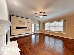 Fate house for rent - an empty living room with wood floors and a large window and a ceiling fan
