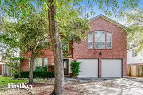 Spring house for rent - a brick house with two garage doors and trees