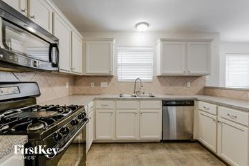 Spring house for rent - a kitchen with white cabinets and stainless steel appliances