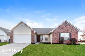 Indianapolis house for rent - A brick house with a garage door and a sign that says "FirstKey Homes".