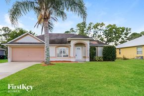 Port St. Lucie house for rent - a pink house with a palm tree in the yard