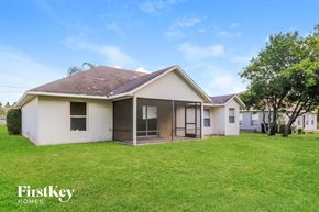 Port St. Lucie house for rent - a small white house with a grassy yard and some trees