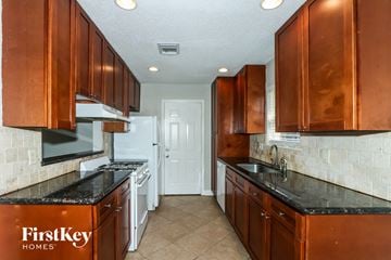 Richmond house for rent - A kitchen with brown cabinets and a black counter top.