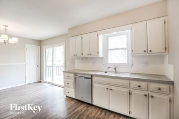 Kansas City house for rent - a kitchen with white cabinets and a sink and a window
