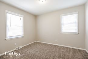 Kansas City house for rent - a bedroom with two windows and a carpeted floor