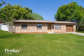 Deltona house for rent - A house with a brown roof and a brown garage door is surrounded by a green lawn.