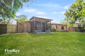 Deltona house for rent - A house with a brown roof and a glass door is surrounded by a fence and green grass.
